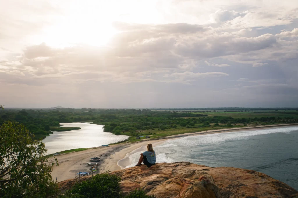 A girl sits on the top of Elephant Rock at sunset in Sri Lanka