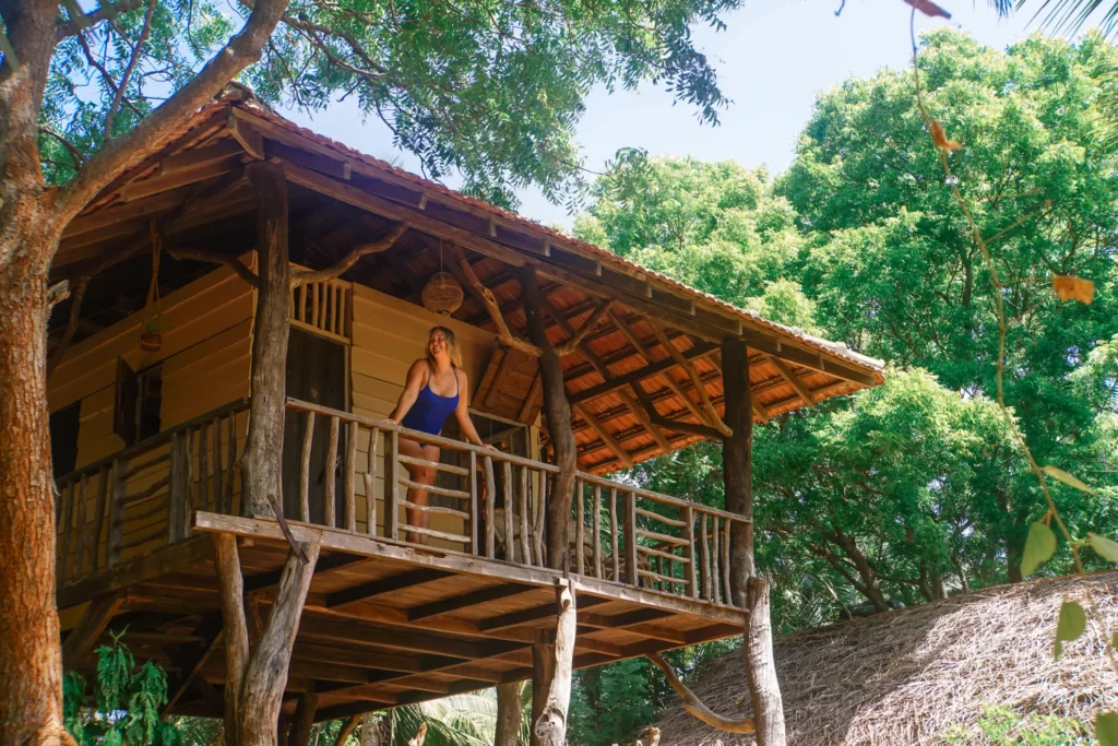 A women stands on the balcony of a stilted cabana at Lighthouse Beach Arugam Bay