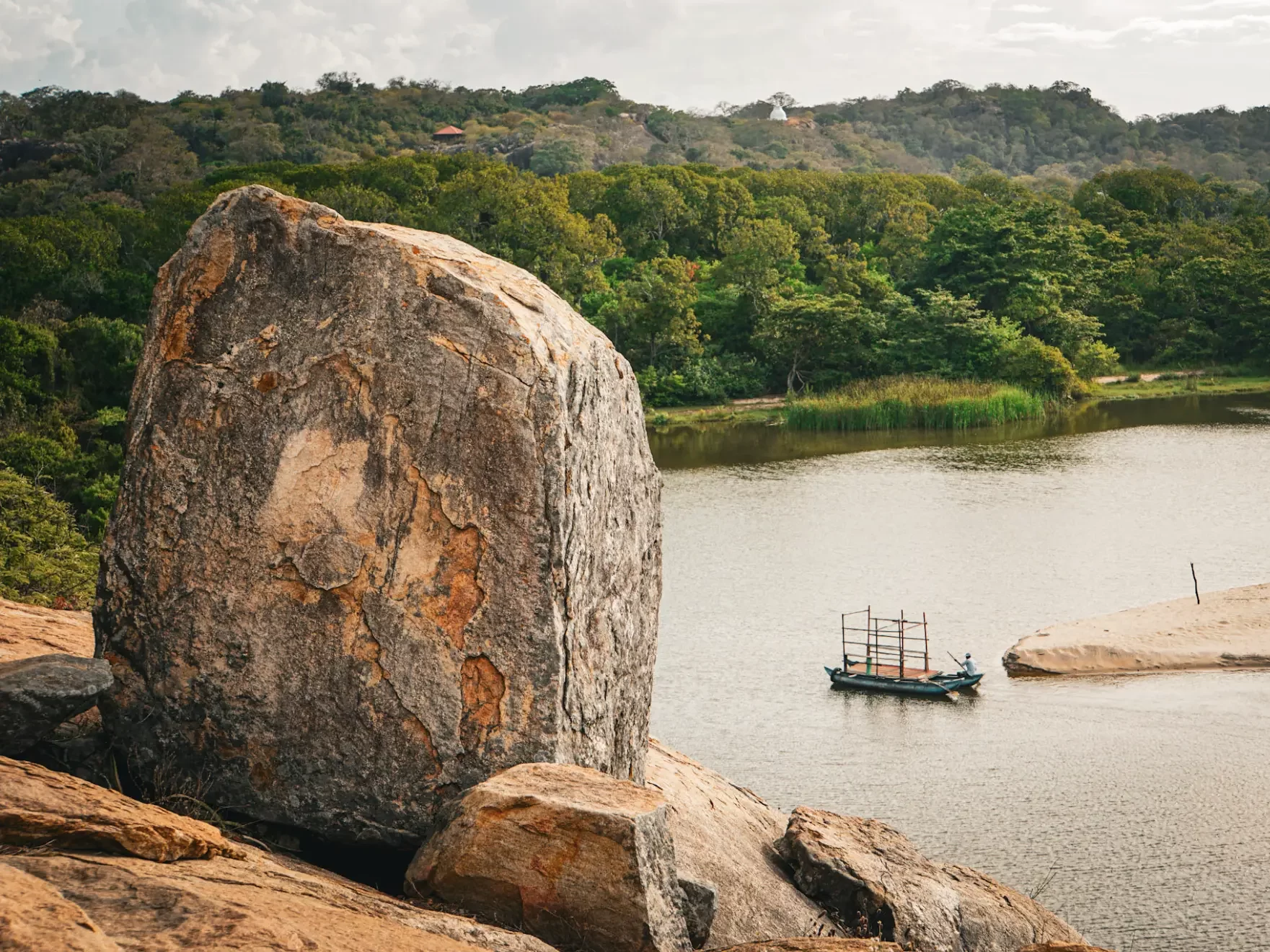 The view of the jungle whilst a man in a makeshift boat cross the lagoon from the top of elephant rock