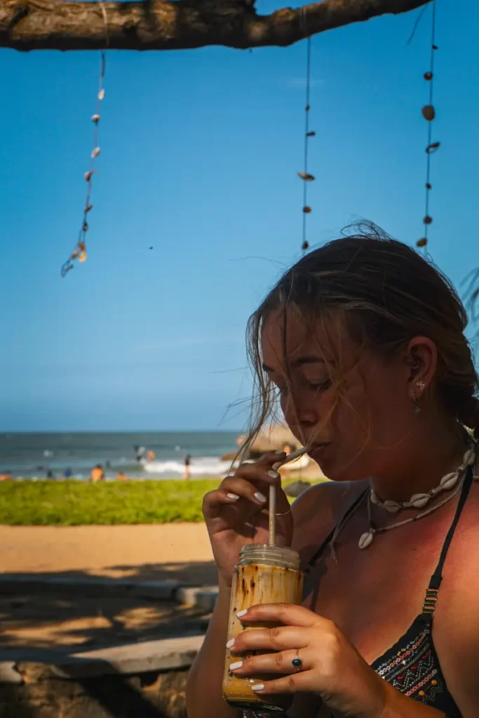 A girl drinking an ice coffee from the cafe at Peanut Farm Beach