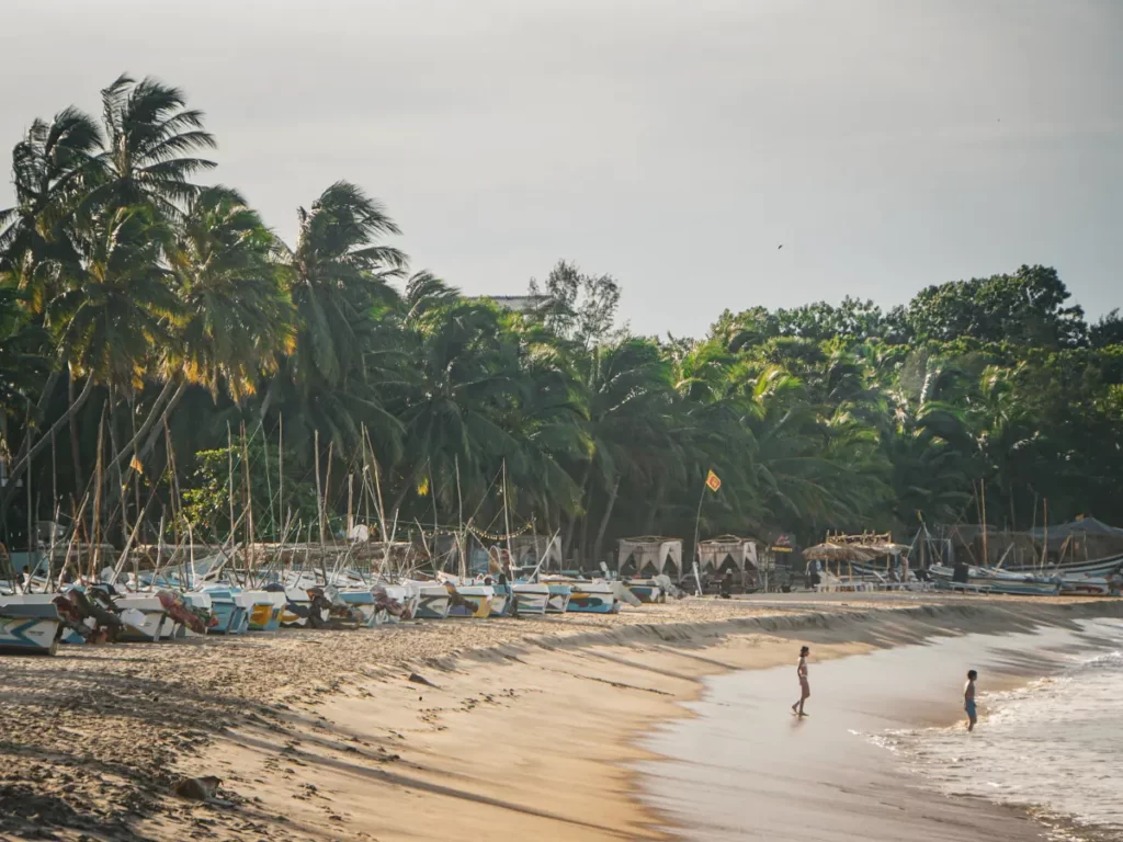 Two local kids play in the ocean on Arugam Bay beach at dusk