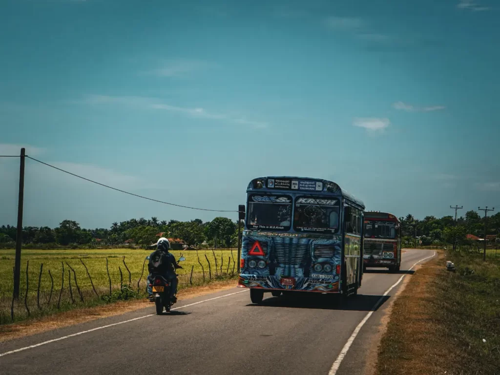 Two buses drive past a motorbiker in Sri Lanka