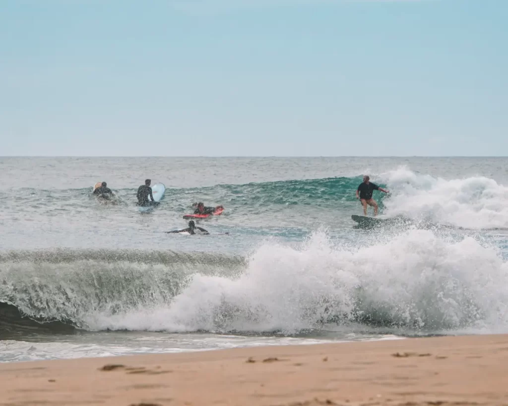A man on a right hand wave at Peanut Farm Beach cutting towards some beginners