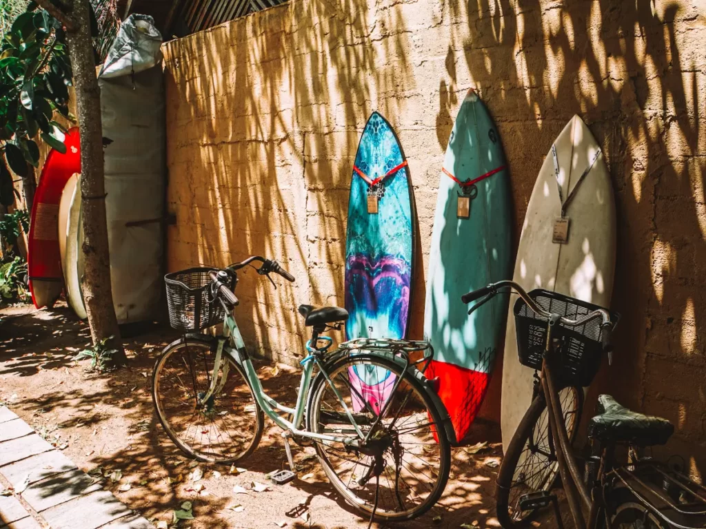 A bike is next to three surfboards against a work in Arugam Bay