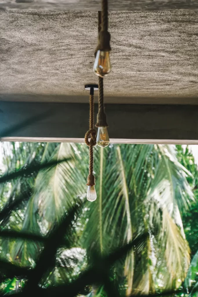 Three lights hand from the ceiling with palm trees in the background in Arugam Bay