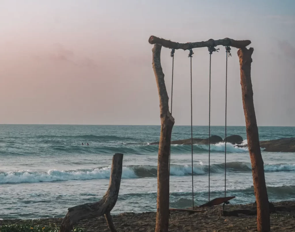 A makeshift swing in the foreground and surfers in the background at sunrise at Lighthouse surf spot