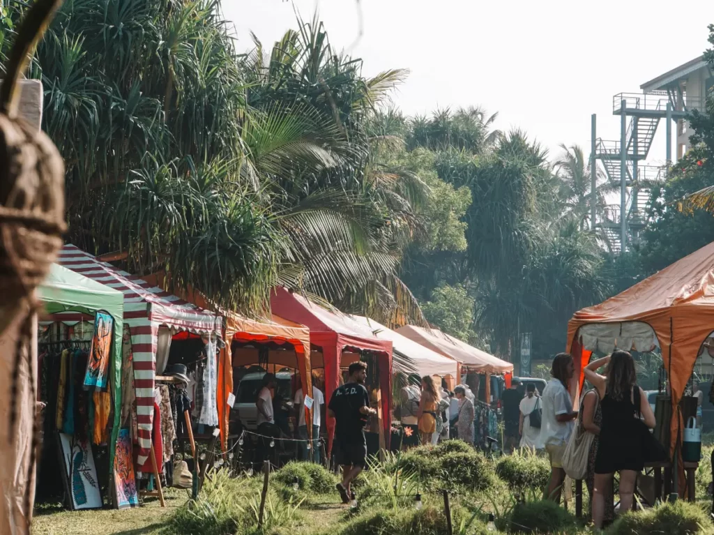 A man walks through the market stalls with palm trees at Cafe Ceylon
