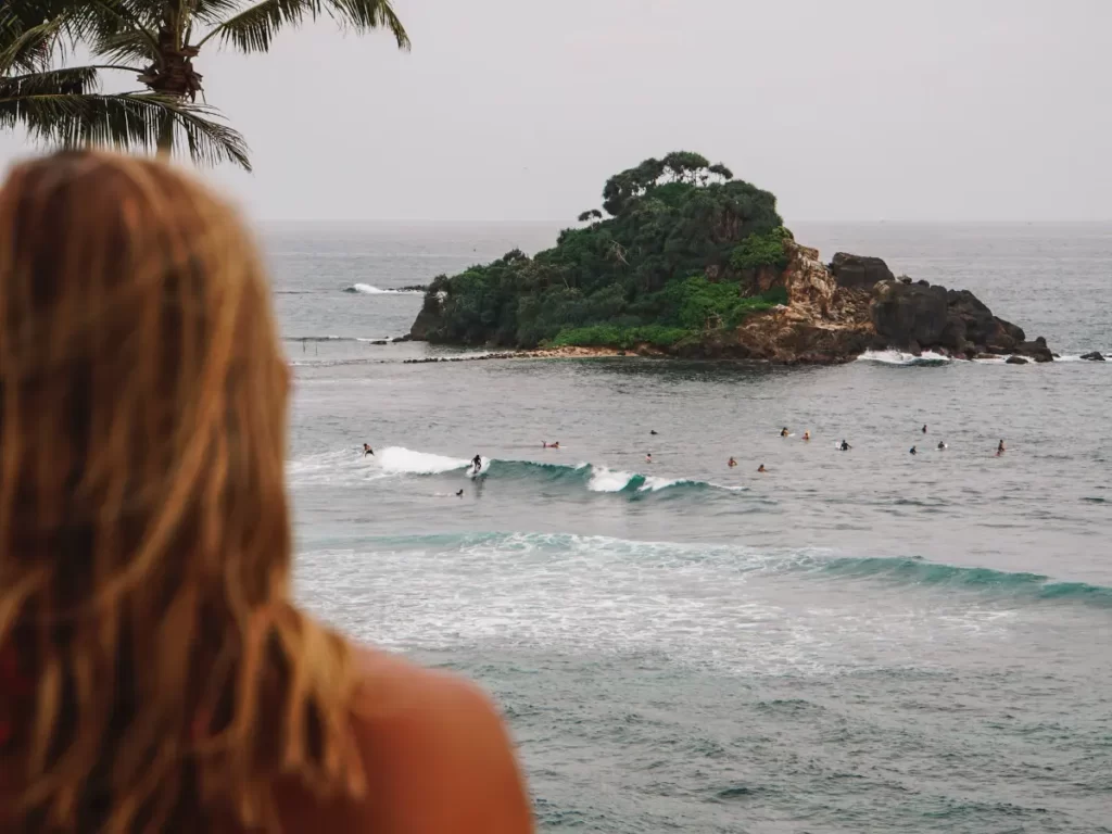 A girl watches the surfers at Sion / Devils rock from Lighthouse rooftop