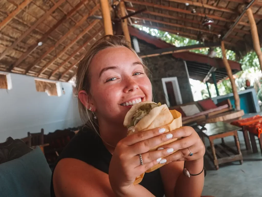 A girl looking happy as she eats a pita wrap at East Falafel in Arugam Bay