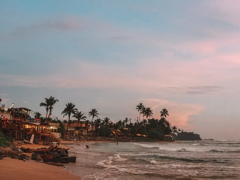 A side view of the restaurants and sand at Ahangama Beach at sunset