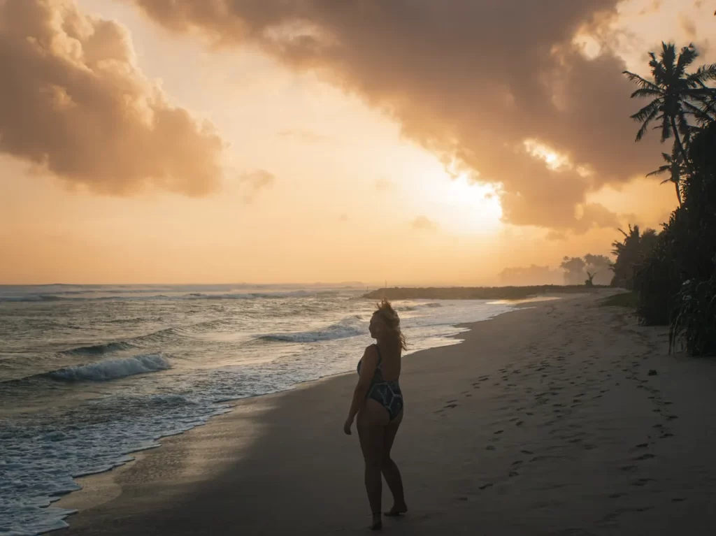 A silhouette girl walking up Ahangama Beach at sunset