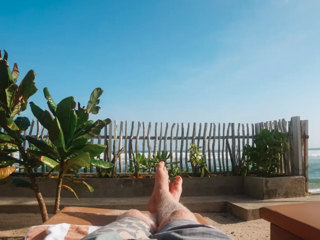 A mans legs at the end of a sun lounger at Lihinya Beach Hotel