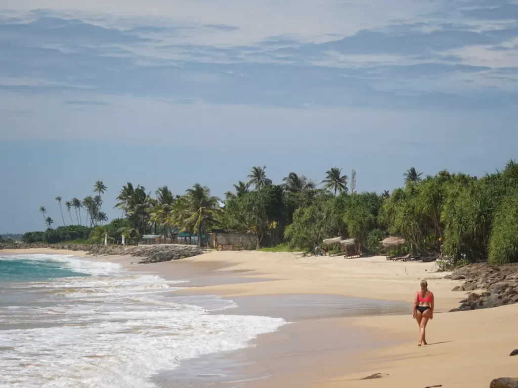 A girl walking down a deserted south beach in Ahangama