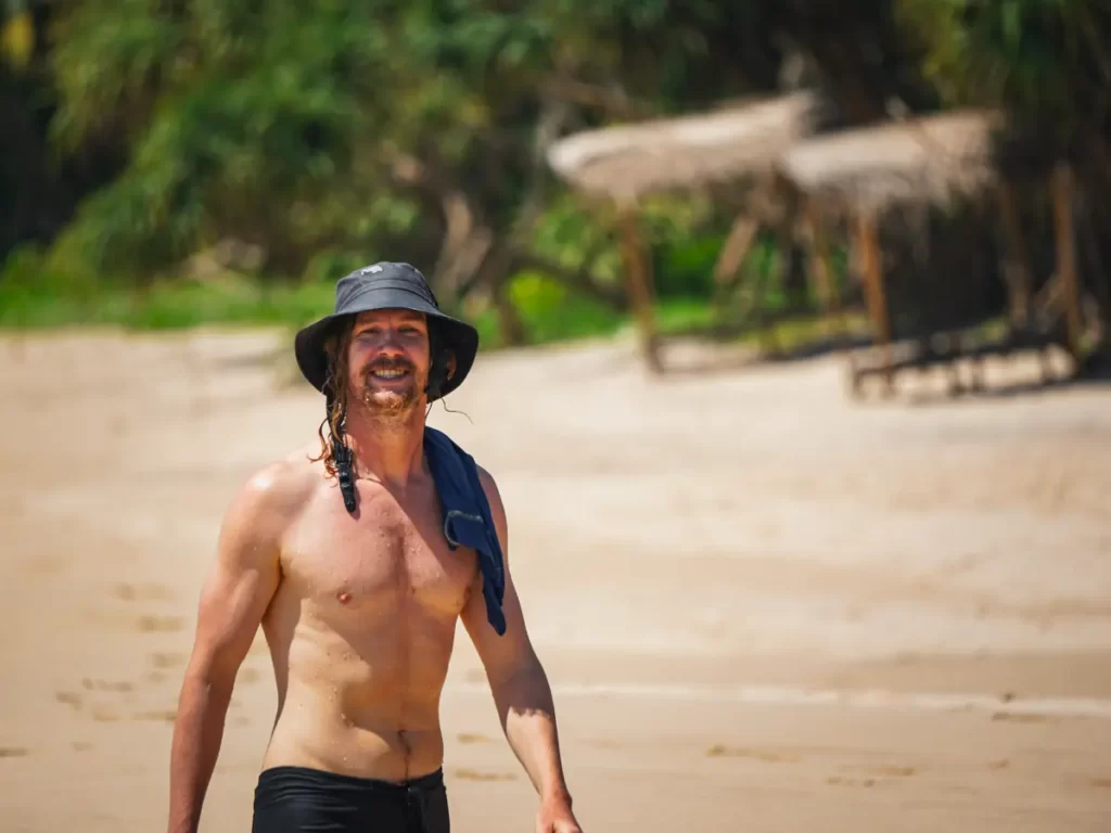 A happy man walking up the beach after a surf at South Beach