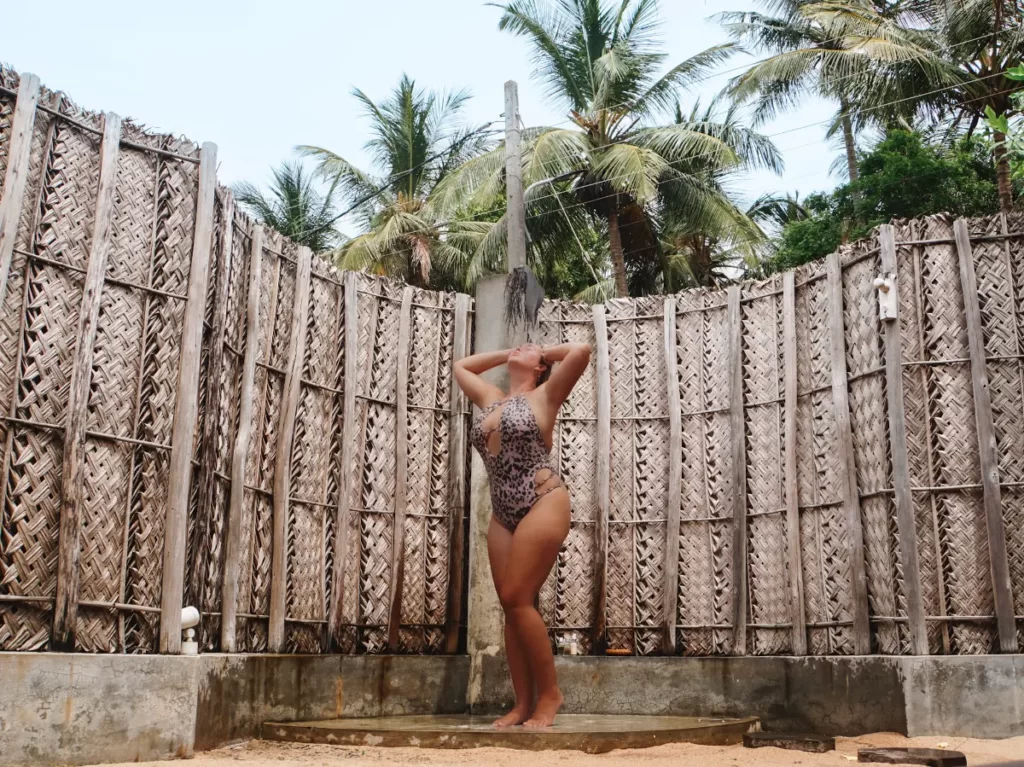 A girl showers outdoor in Jetwing Surfs bathrooms