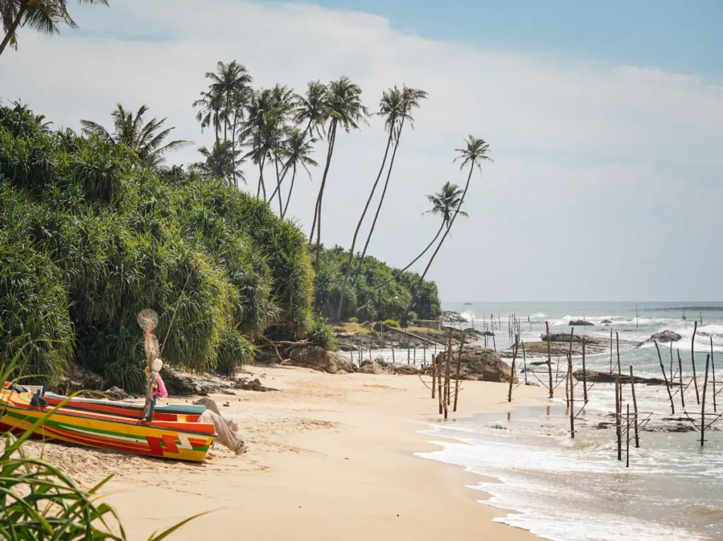A few fishing boats on the beach and many stilts for fishing in the ocean at Koggola Beach