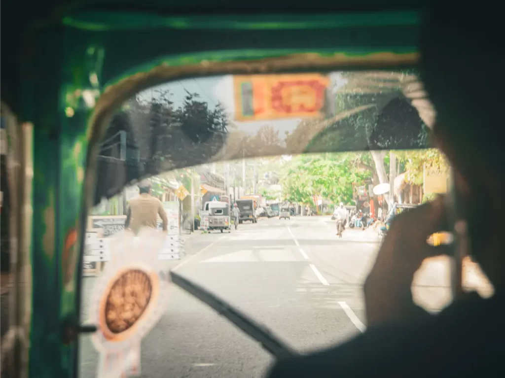 A man drives a Tuk Tuk down a road in Sri Lanka