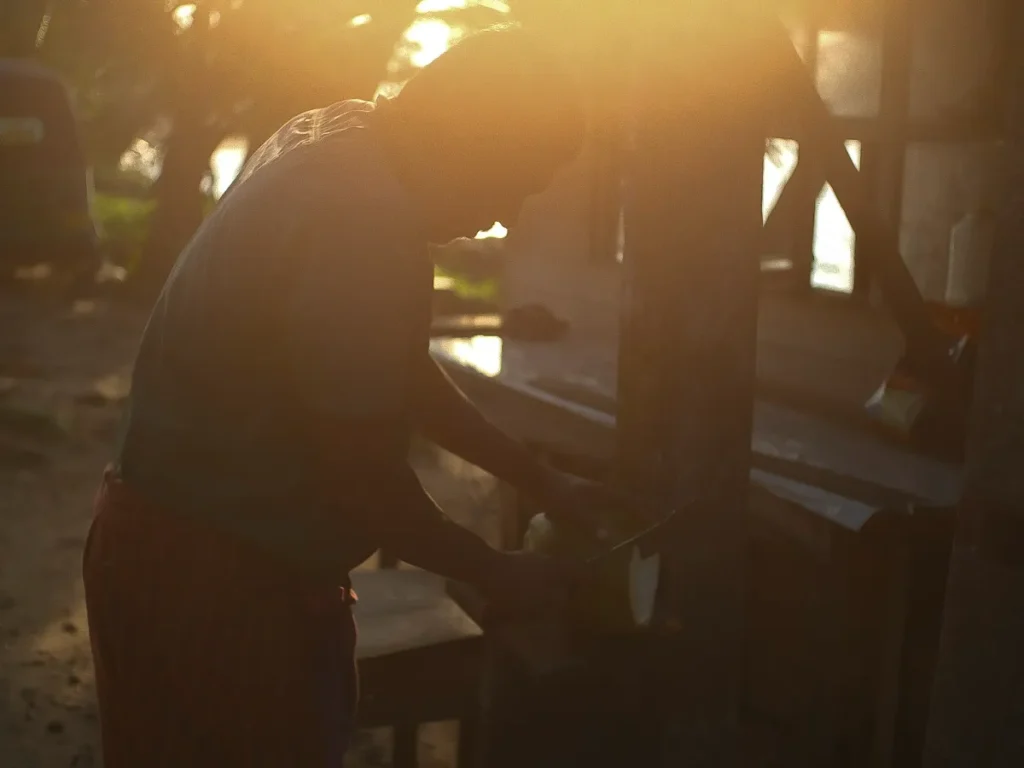 A local man cutting a coconut at sunrise in Madiha