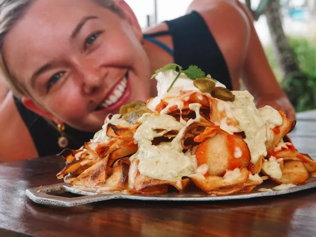 A girl smiles behind the giant nacho plate severed at The Doctors House for lunch