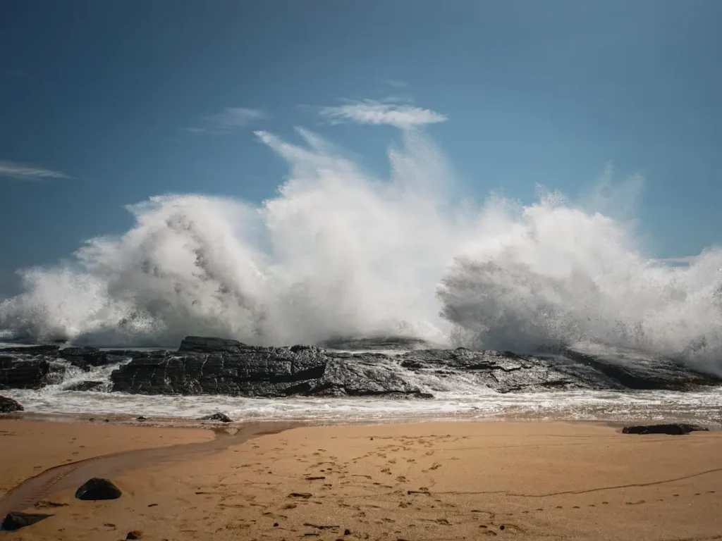 Giant waves crash on some rocks on an isolated beach in Madiha