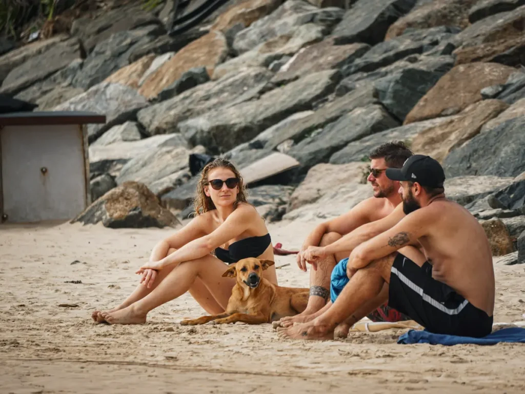 3 friends and a dog sitting on the sand on Ahangama Beach