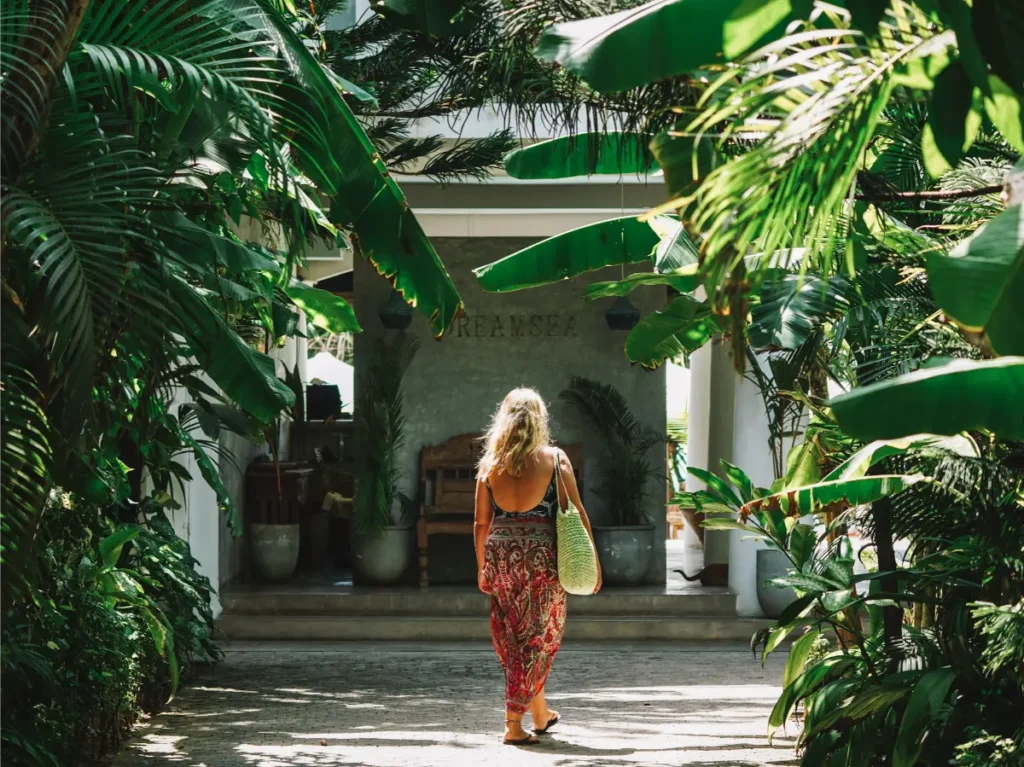 A girl walking through the jungle entrance of Dreamsea Surf Camp in Ahangama