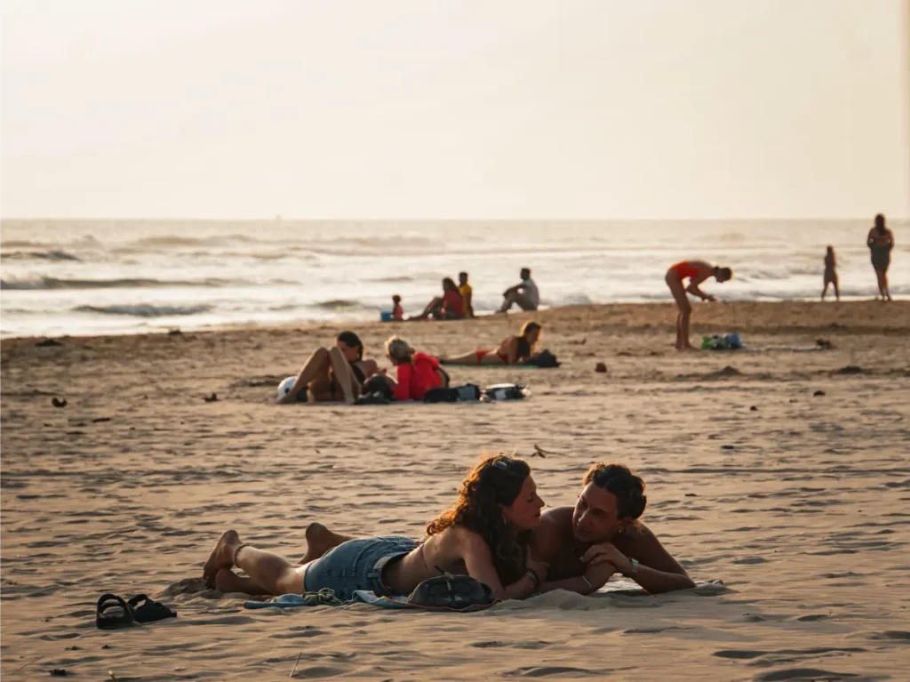 Two people lie on the sand chatting and being social at Kabalana Beach