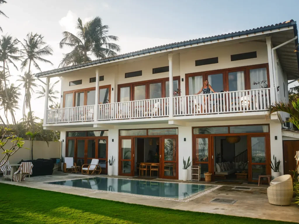 A front facing view of Lihinya with a girl standing on her balcony and the pool in the foreground