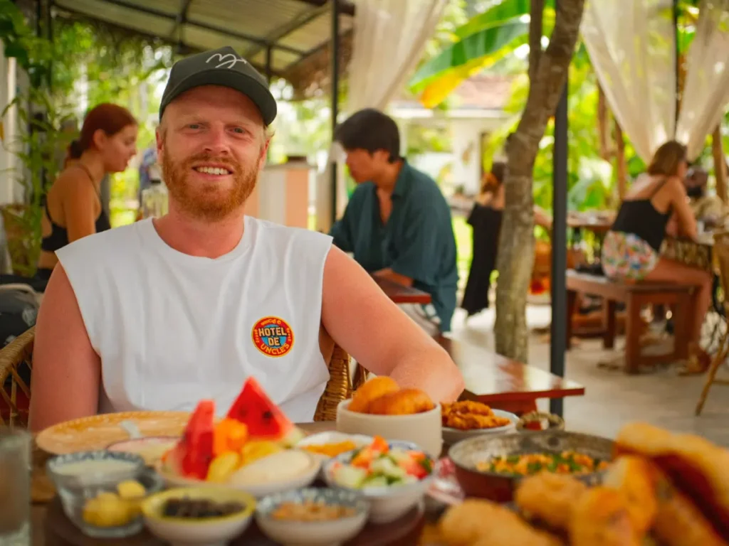 A man sits in the Sisters Away garden with a Turkish Breakfast in front of him