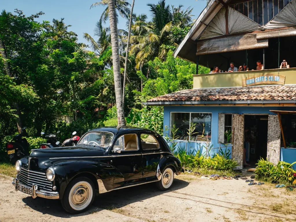 A classic car parked in front of the Veda Cafe restaurant