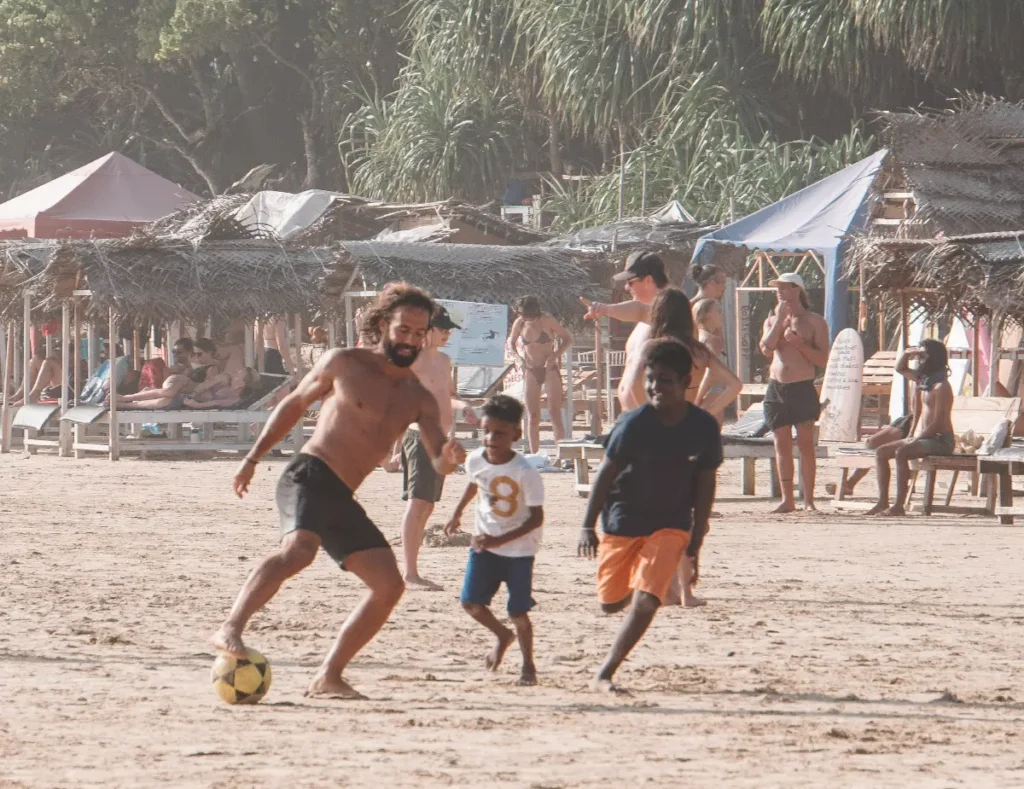 A man plays football with the local kids on Kabalana Beach