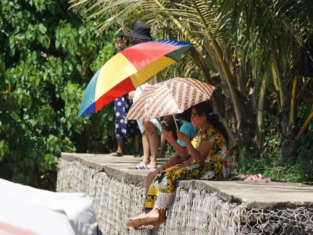 Local Sri Lankans sitting on a seawall with umbrellas