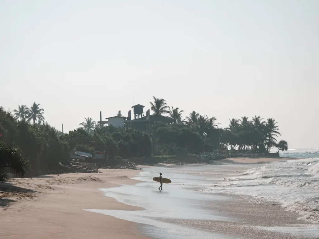 A surfer standing on South Beach in Ahangama