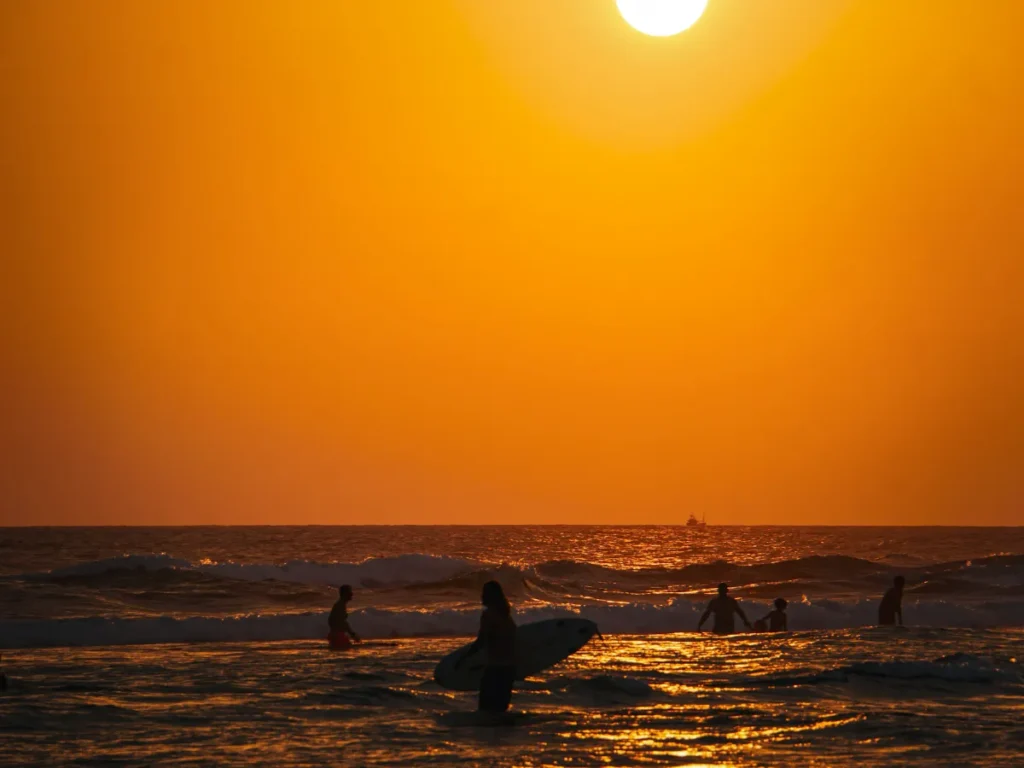 Silhouettes of surfers at Kabalana Beach at sunset 