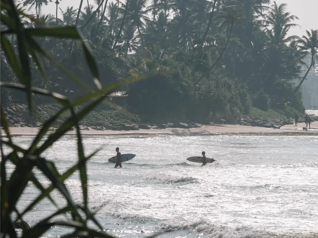 Two surfers walking out of the ocean at Ahangama Beach