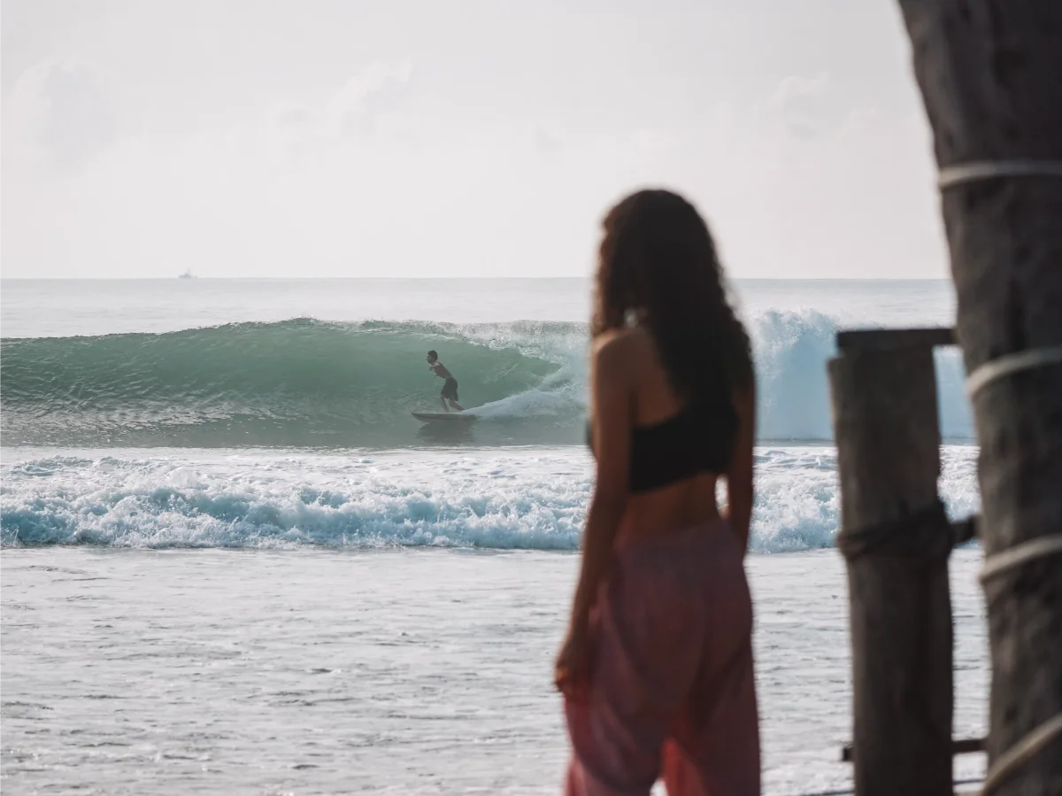 A girl watches a surfer on Main Point in Arugam Bay