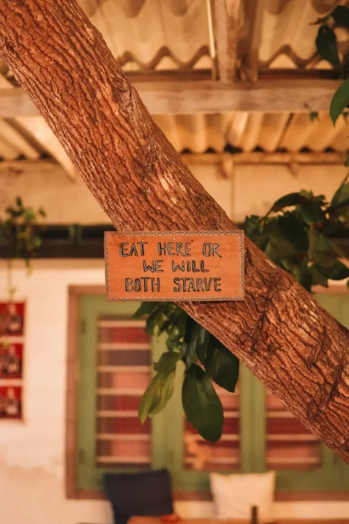 A sign saying eat here or we will both starve in a restaurant in Madiha