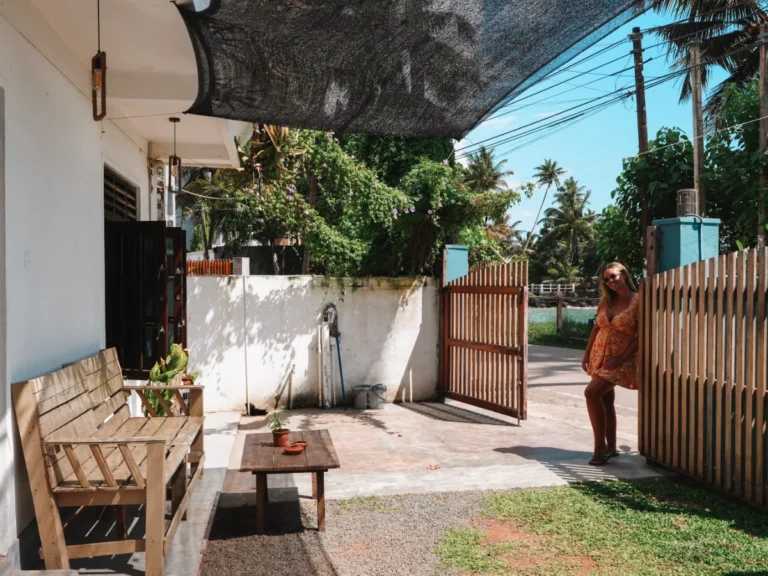 A girl stands next to the gate of Just Another Guesthouse, a great budget option to choose in Madiha