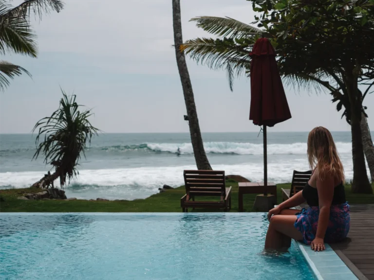 A girl sits in Villa Oceane's pool watching the surfers on the waves