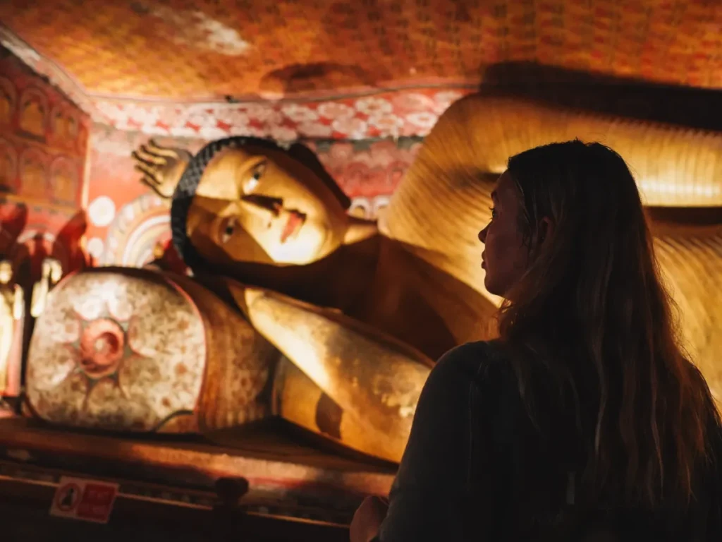 A girl admires the artwork near a lying Buddha at the Dambulla Cave Temple