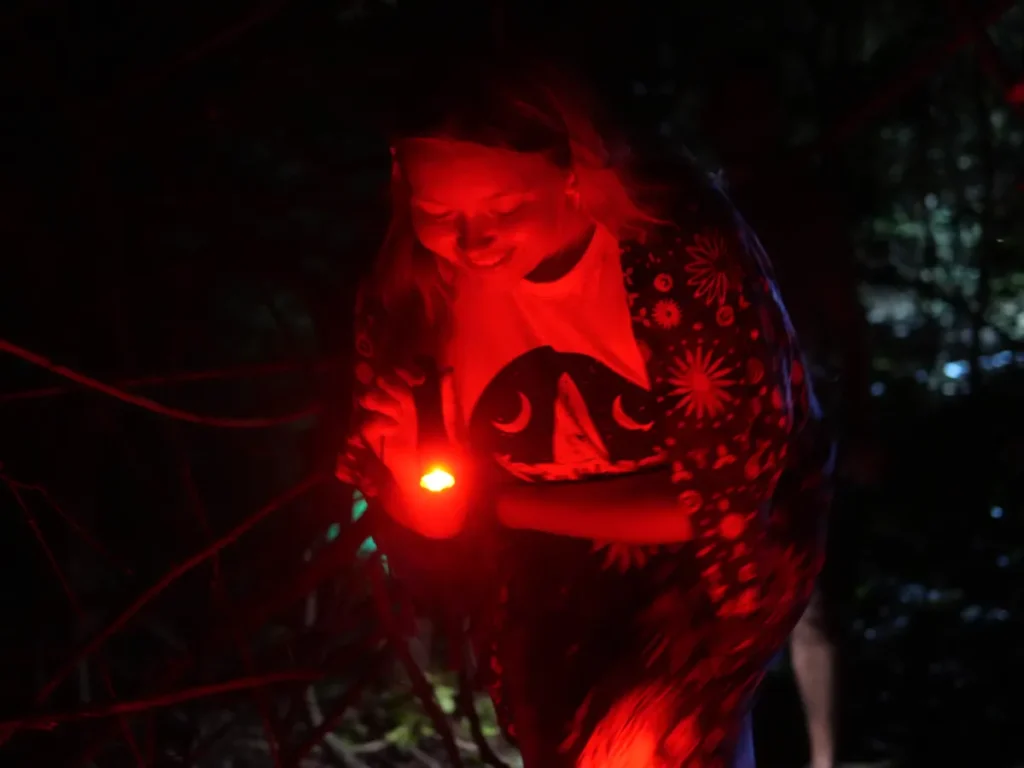A girl shines her red torch at the ground on a night hike in Sigiriya