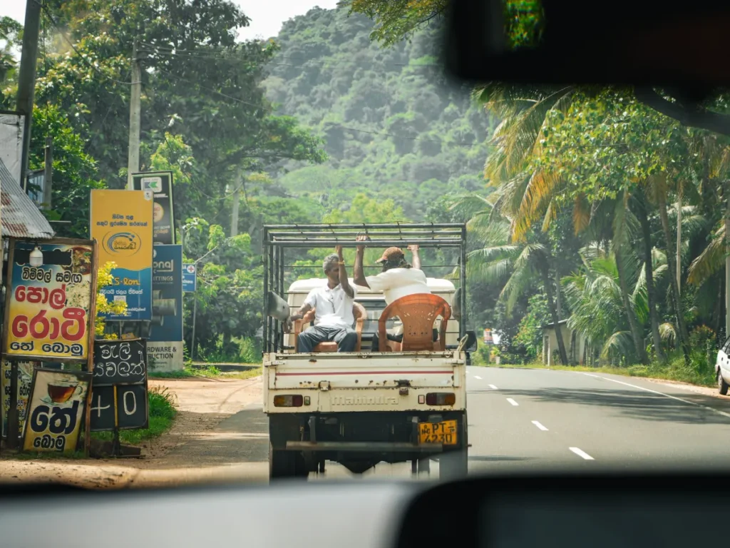 Two local men ride in the back of a pickup truck in Sigiriya