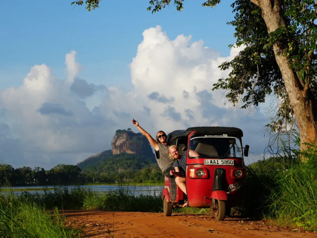 Two travellers sitting in a Tuk Tuk with Sigiriya in the background