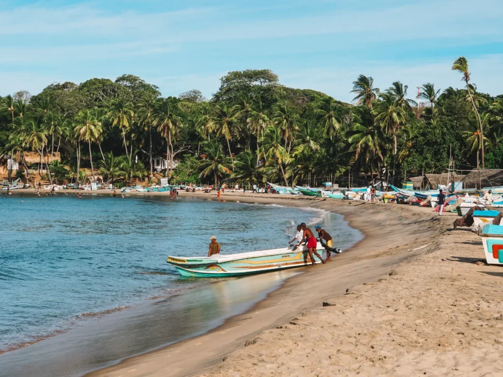 A group of fishermen push a boat into the water in Arugam Bay