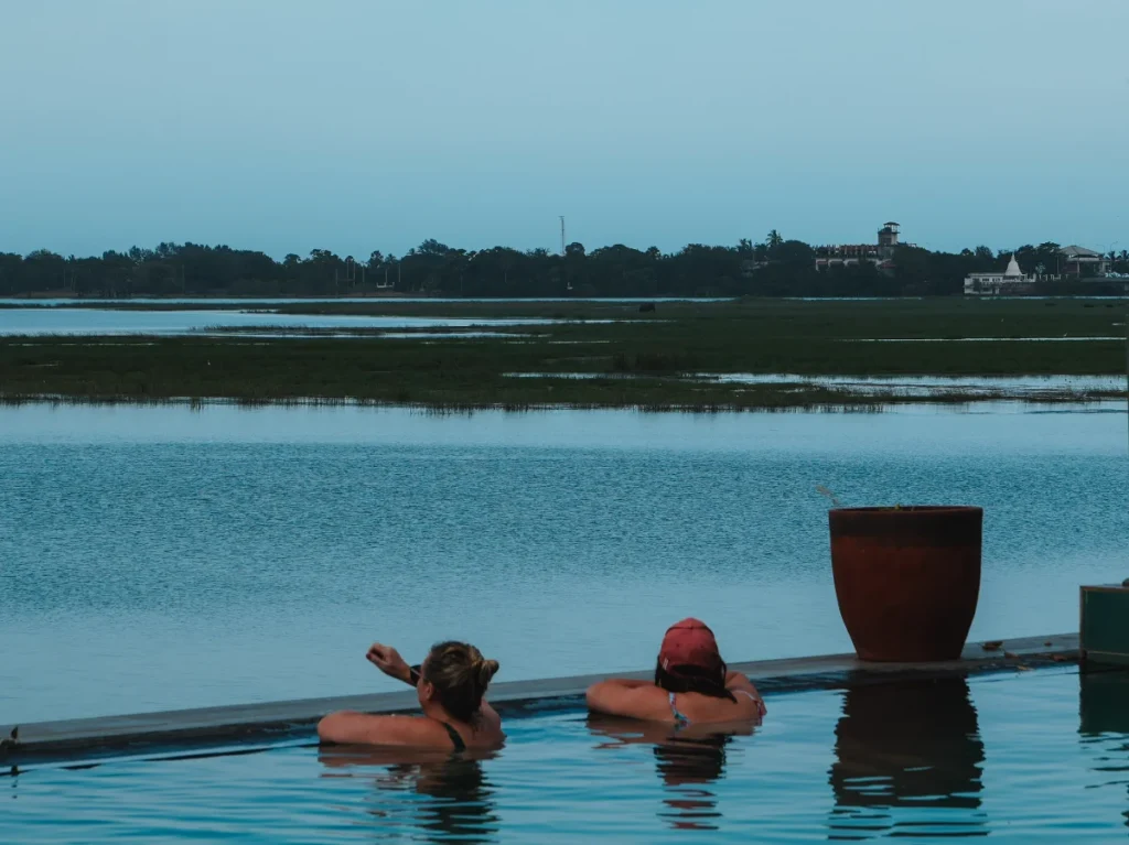 Two people watch an Elephant in the lagoon as they swim in Oruwa Boutique Villas infinity pool