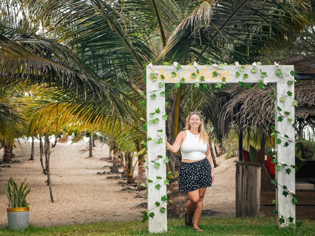 A girl stands under the archway shower at Stay Golden