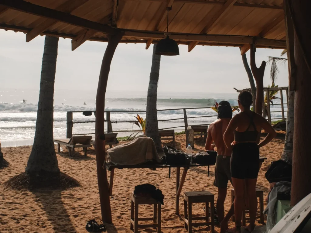 A couple watches a surfer catch a wave at Main Point from Upali Beach Resort, a top budget place to stay