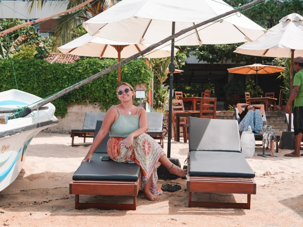 A girl sits on the sun loungers on the beachfront outside Bay Vista, a top place to stay in Arugam Bay