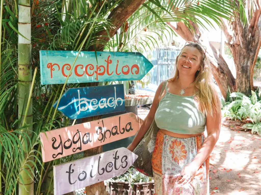 A girl stands next to the funky signs at Waypoint Arugam Bay